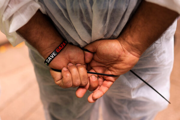The hands of a protestor dressed as a Palestinian prisoner are seen in plastic handcuffs wearing a ‘save Gaza” wristband during a Pro-Palestine demonstration in Sydney, Sunday, February 11, 2024. (AAP Image/Mark Evans) NO ARCHIVING