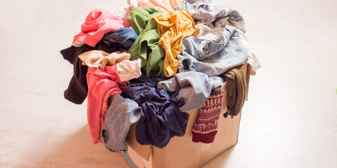 Pile of clothes in a large cardboard box. Sorting wardrobe and decluttering