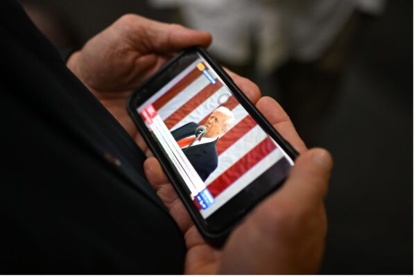 A journalist watches an announcement on tariffs by US President Donald Trump on Day 6 of the 2025 federal election campaign, in Melbourne, Thursday, April 3, 2025.